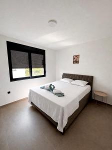 a bedroom with a large white bed with a window at Apartments Lialda in Donji Štoj