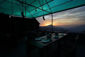 a table with plates of food on it with the sunset at Camping in Chail in Chail +2 photos