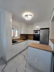 a kitchen with white cabinets and a black appliance at Braavos apartments Šibenik Deluxe near Marina in Šibenik