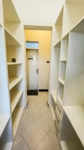 a walk in closet with white shelves and a door at Bwebajja Hub in Bwebajja +8 photos