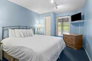 a blue bedroom with a white bed and a television at 110 Pointes North Inn in Charlevoix +14 photos