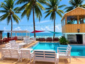 a pool with white chairs and tables and palm trees at Ileero Homes The Beachfront in Lekki