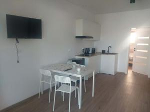 a white table and chairs in a room with a kitchen at Miskant Apartamenty in Stary Karwno