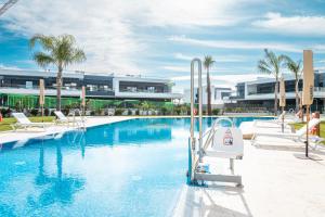 a large swimming pool with chairs and a building at CasaBlanka Premium Apartment with Pool & Wellness in Torrevieja +69 photos