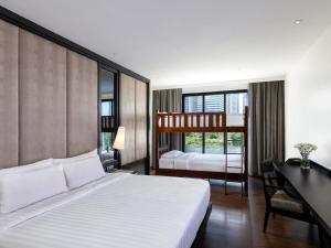 a bedroom with a bed and a desk and a bunk bed at Mövenpick Hotel Sukhumvit 15 Bangkok in Bangkok