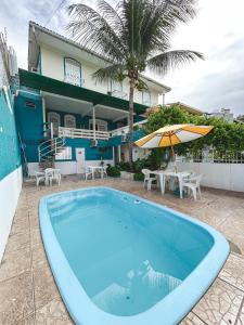 a swimming pool with an umbrella and a house at Pousada Nossa Natal in Natal