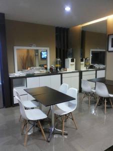 a kitchen with two tables and white chairs and a counter at Radiant Hotel in Sitiawan