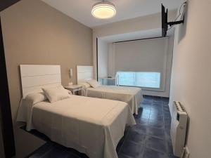 a hotel room with two beds and a window at HOSTAL CASA JULIO - Auto Check-in in Culleredo
