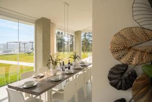 a dining room with a long table and white chairs at VILLA OXA 12&2, Emma Villas in Imola