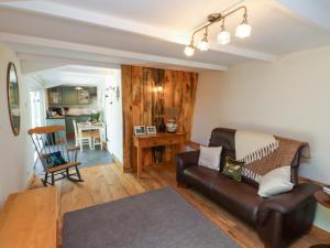 a living room with a leather couch and a table at Woodman's Lodge in Moelfre