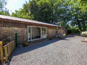 a stone house with a window and a swing at Woodman's Lodge in Moelfre