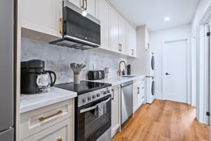 a kitchen with white cabinets and a stove top oven at Casa Hotels Gerrard Modern Downtown Suite in Toronto