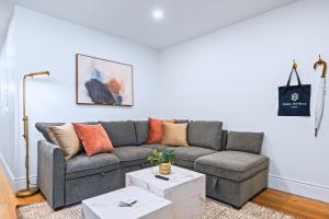 a living room with a gray couch with orange pillows at Casa Hotels Gerrard Modern Downtown Suite in Toronto +17 photos