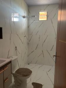 a white bathroom with a toilet and a shower at Casa vini in Viçosa do Ceará