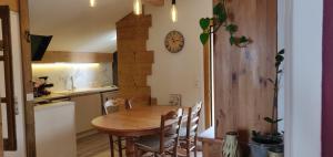 a kitchen with a wooden table and a clock on the wall at Le nid bucolique in Publier