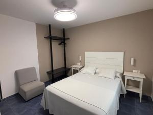 a bedroom with a white bed and a chair at HOSTAL CASA JULIO - Auto Check-in in Culleredo
