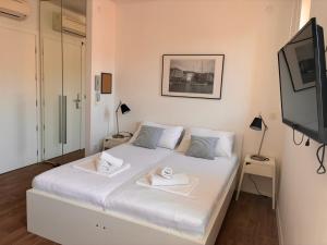 a white bed in a room with a flat screen tv at Ridzak Riva Rooms in Mali Lošinj