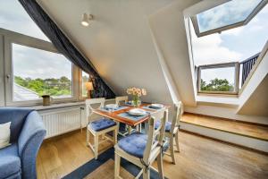 a dining room with a table and chairs and windows at Liiger-Hoern-DG-Wohnung-4-Moewe in Tinnum