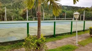 a tennis court with a palm tree next to a fence at Apartamento Hotel Cavalinho Branco in Águas de Lindoia