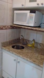 a kitchen counter with a sink and a microwave at Apartamento Hotel Cavalinho Branco in Águas de Lindóia
