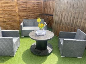 a patio with two chairs and a table with flowers on it at Un écrin chic à deux pas de la mer in Merlimont +3 photos