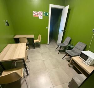 a waiting room with green walls and tables and chairs at Hostel BM19 in Madrid