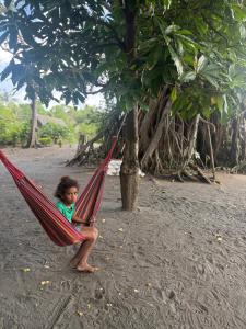 a little girl sitting in a red hammock under a tree at Fireworks Tree House in White Sands