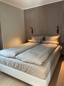 a large bed with white sheets and pillows at City Svolvær Apartment in Svolvær