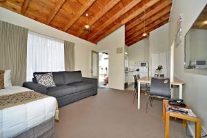 a room with a bed and a couch and a table at Takapuna Motor Lodge in Auckland