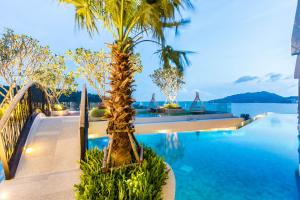 una piscina con una palmera junto al agua en Crest Resort & Pool Villas - SHA Extra Plus en Patong Beach