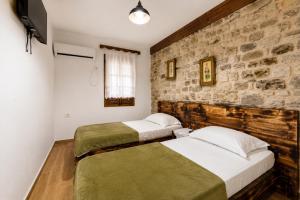two beds in a bedroom with a stone wall at Kitarat Berat Castle in Berat