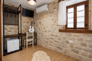 a room with a brick wall and a chair and a guitar at Kitarat Berat Castle in Berat