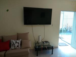 a living room with a couch and a tv on the wall at house on the hill in Nagua