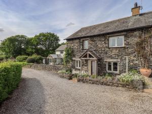 an old stone cottage with a gravel driveway at Kestrel Cottage in Grange Over Sands