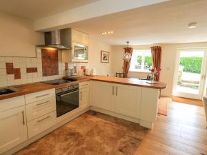 a kitchen with white cabinets and a counter top at Kestrel Cottage in Grange Over Sands