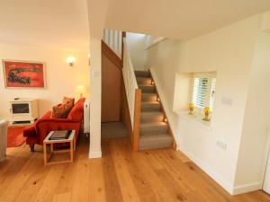 a living room with a staircase and a red couch at Kestrel Cottage in Grange Over Sands