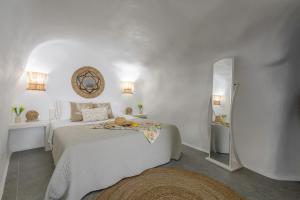 a white bedroom with a bed and a mirror at Esperanza Fisherman Houses in Mandrakia