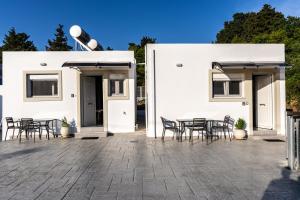 a patio with chairs and tables in front of a white building at Aroma Zia Residences 2 in Lagoúdi Zía