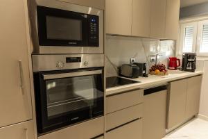a kitchen with a microwave oven and a sink at Aroma Zia Residences 2 in Lagoúdi Zía