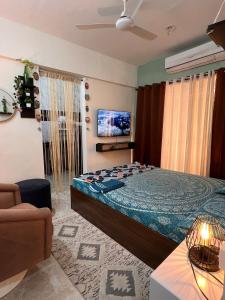 a bedroom with a bed and a couch and a tv at Sugar Waves in Navi Mumbai