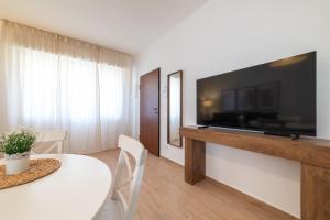 a living room with a white table and a flat screen tv at Casa MaMi in Gatteo a Mare