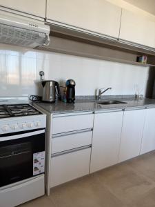 a kitchen with white cabinets and a stove at Moras Urban in Esperanza
