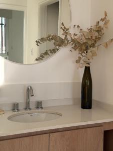 a bathroom sink with a vase with flowers in a bottle at Moras Urban in Esperanza