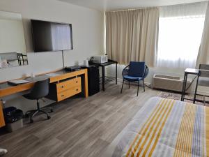 a hotel room with a bed and a desk and chairs at Auberge Cap Martin in La Pocatiere