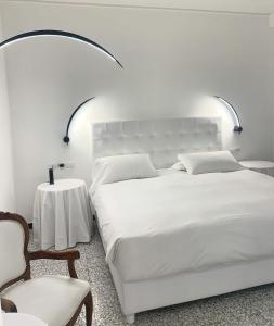 a white bedroom with a large bed and a table at Eveline 2 - Piscina Privata o Jacuzzi in Sanremo