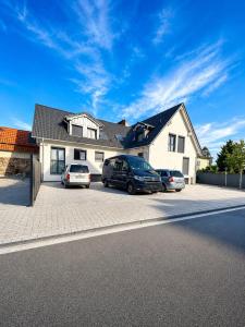 two cars parked in a parking lot in front of a house at Neubau, Luxus, 3-Zi Wohn für KaffeeGenießer in Eggenstein