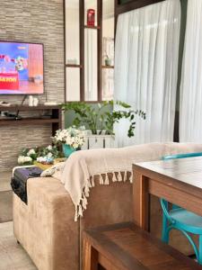a living room with a couch and a tv at Quarto 5J Joinville Costa e Silva perto Centro in Joinville