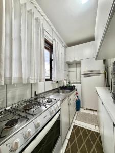 a white kitchen with a stove and a sink at Quarto 5J Joinville Costa e Silva perto Centro in Joinville +14 photos