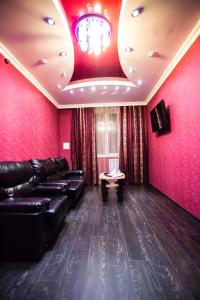 ヤクーツクにあるAlmaz Hotelの赤い壁のリビングルーム(黒い革張りのソファ付)