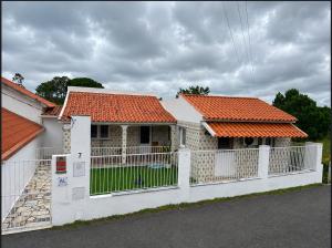 ein Haus mit orangefarbenem Dach und weißem Zaun in der Unterkunft PineHills in Torres Vedras